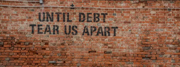 Picture of a wall with the writing "Until debt tear us apart"